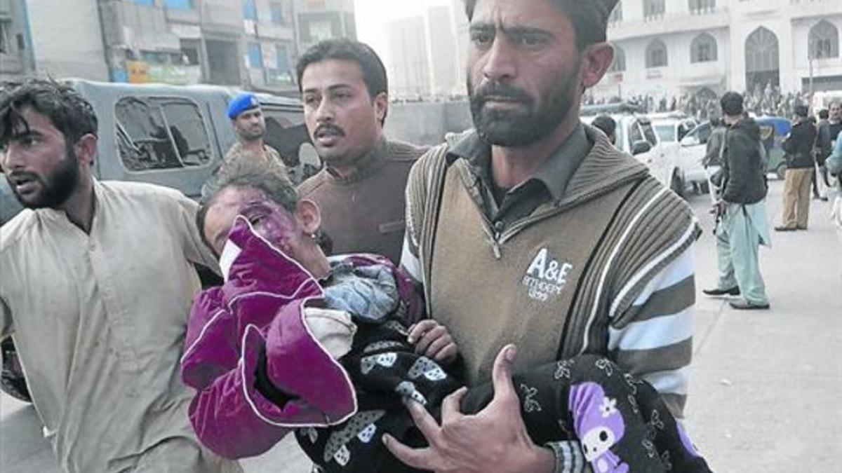 Un hombre traslada a una niña herida en el asalto del comando talibán a una escuela en Peshawar.