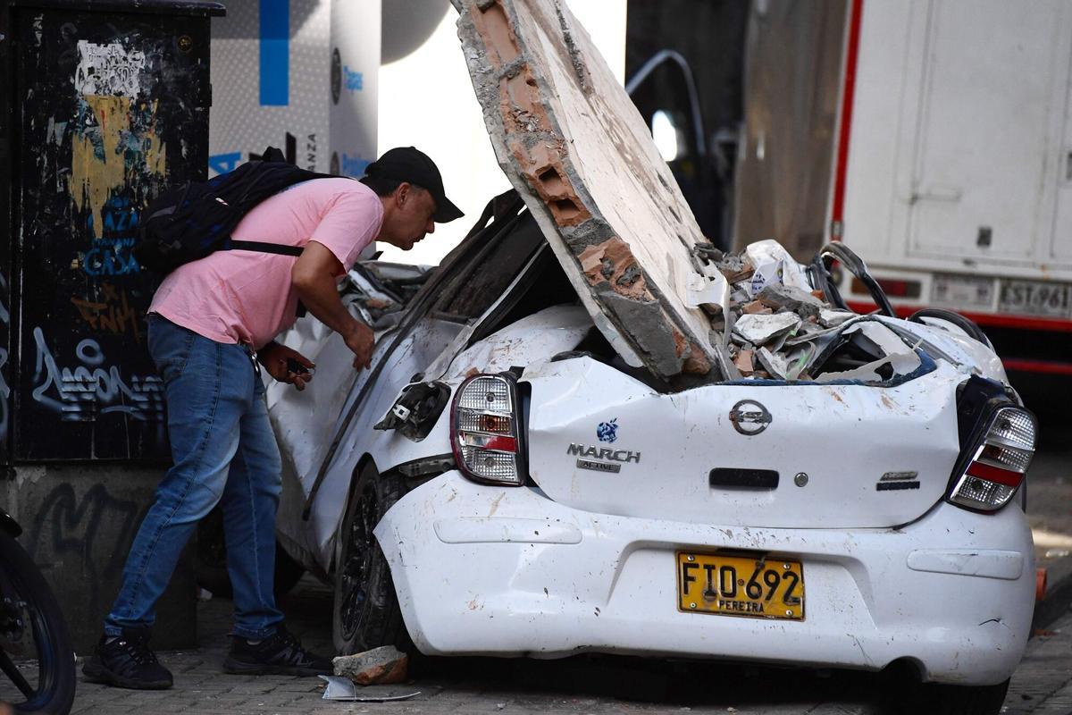 Un hombre mira su coche aplastado por la caída de edificios por el terremoto de 7,4 en Pereira, Colombia