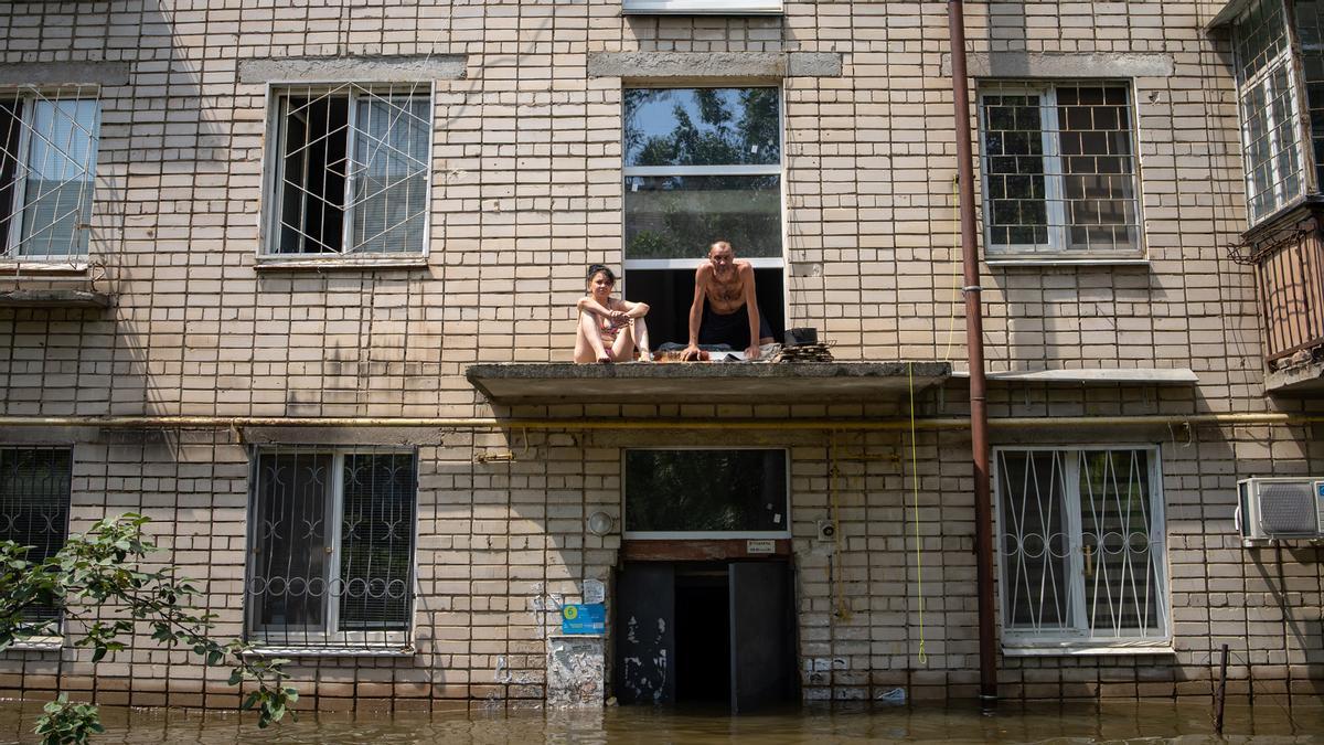 Una pareja observa las calles inundadas de Jersón desde una repisa de un edificio.