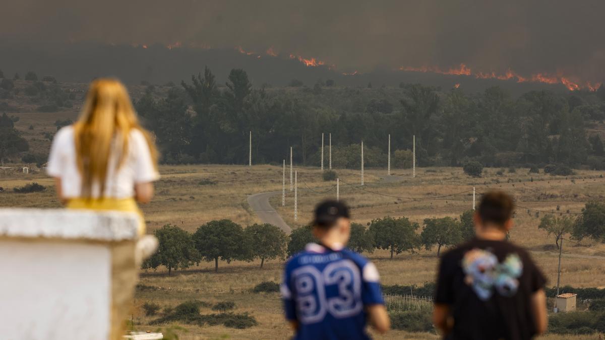 Varias personas observan las llamas y el humo del incendio en Bejís desde el municipio de El Toro.