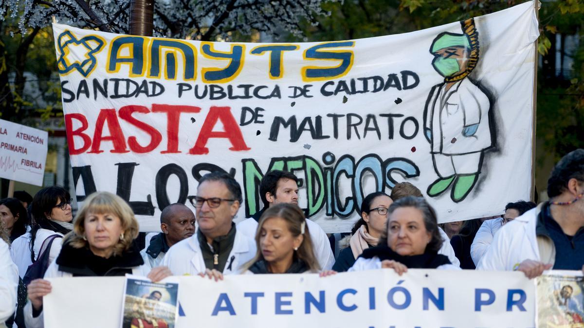 Varias personas con pancartas participan durante una concentración de sanitarios en el arranque de la segunda semana de huelga de médicos y pediatras de Atención Primaria, frente a la Consejería de Hacienda