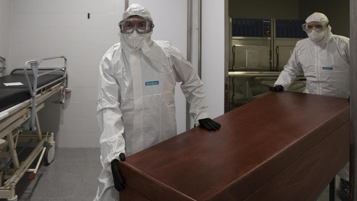 Los funerarios se visten con un EPI para trasladar un difunto fallecido de coronavirus Covid-19 desde la morgue del Hospital de Mataró hasta el tanatorio