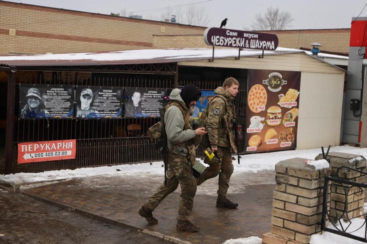 Soldados ucranianos pasean por las calles de Izium frente a las esquelas en memoria de varios compañeros caídos en el frente.