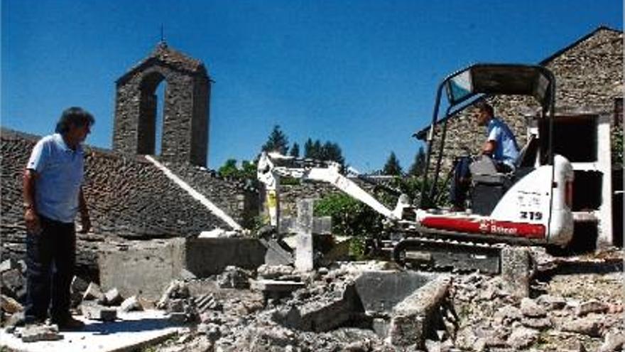 Dos operaris treballant en la retirada de restes de l&#039;antic cementiri amb una petita excavadora.