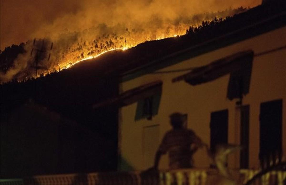 abertran38938929 a man on the balcony of a house looks up at a forest fire ra170618115500
