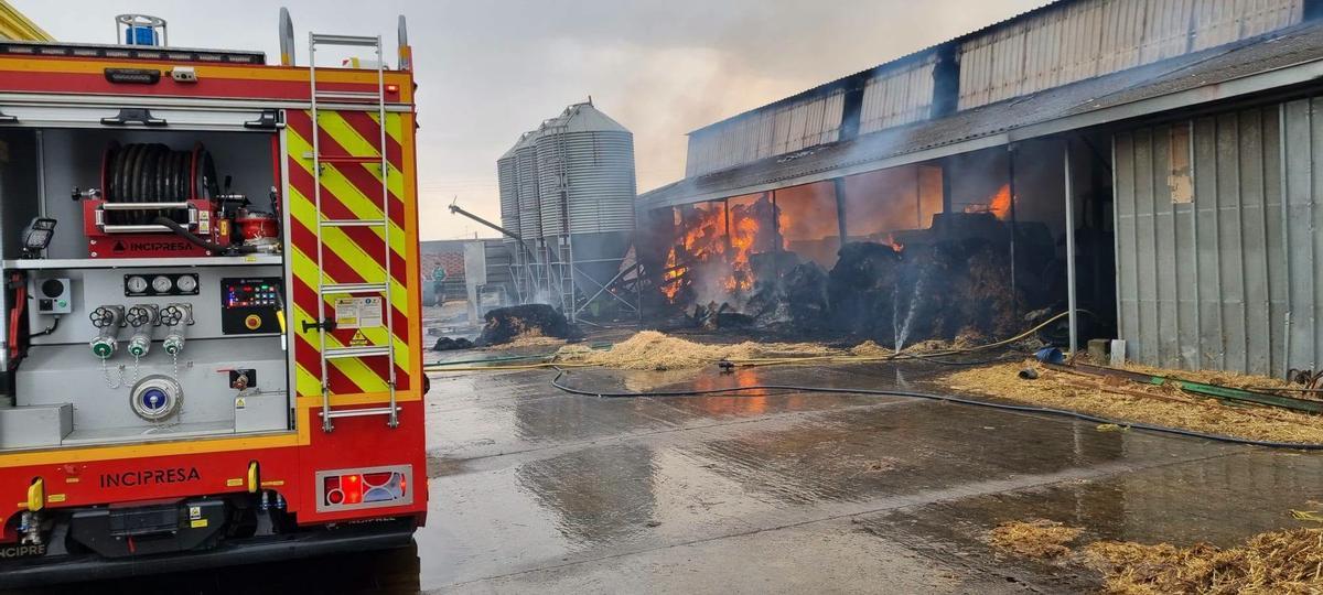 Los bomberos tratan de contener el fuego provocado por la tormenta eléctrica en una de las naves agroganaderas en Cerecinos de Campos.