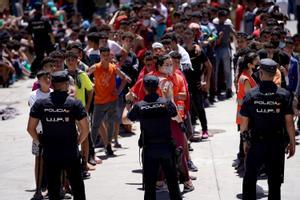 Menores migrantes no acompañados son custodiados por la policía en las naves industriales de Ceuta.