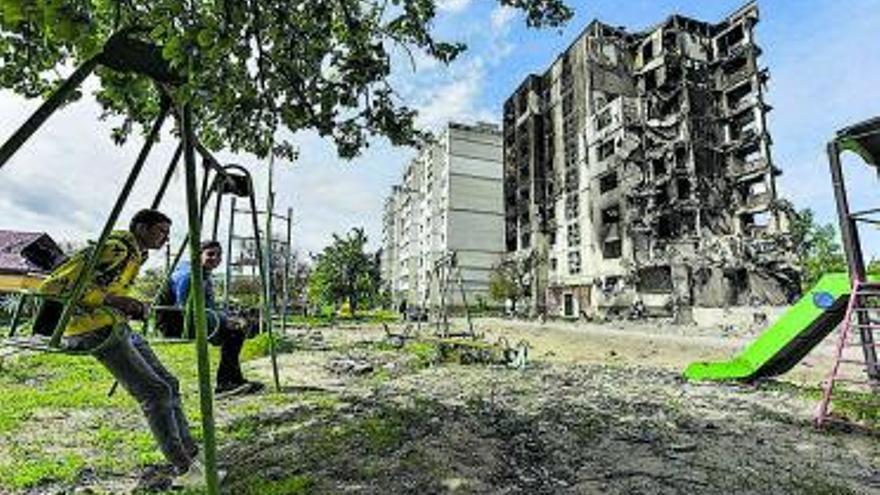 Dos joves,  davant un edifici destrossat a Kíiv | EFE