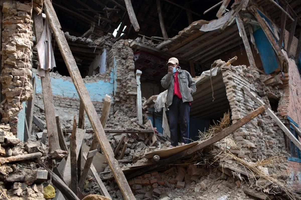 Un home dret entre la runa d’un edifici destruït pel terratrèmol del Nepal.