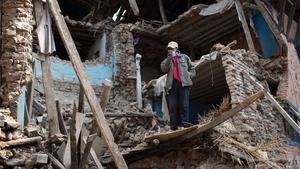 Un home dret entre la runa d’un edifici destruït pel terratrèmol del Nepal.