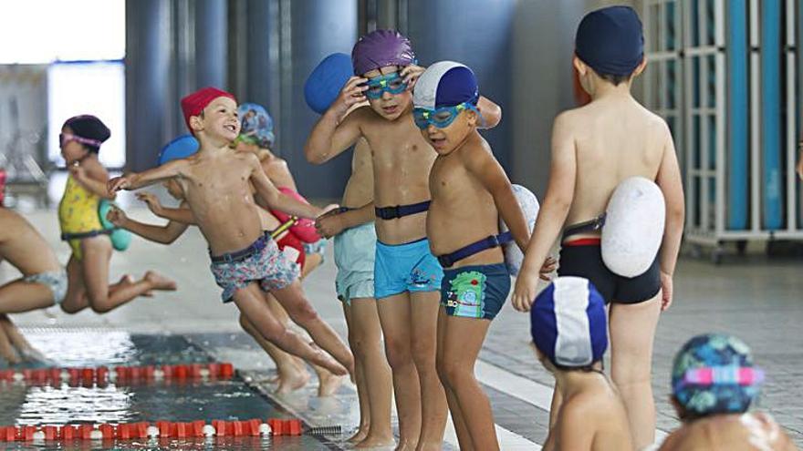 Sobre estas líneas, de arriba abajo, los niños se lanzan a la piscina; Carlos Caicoya se prepara para un lanzamiento, y Gema Suárez y Laura Antón, la monitora, en un descanso. A la derecha, los niños entran a la sala de manualidades. | Luisma Murias