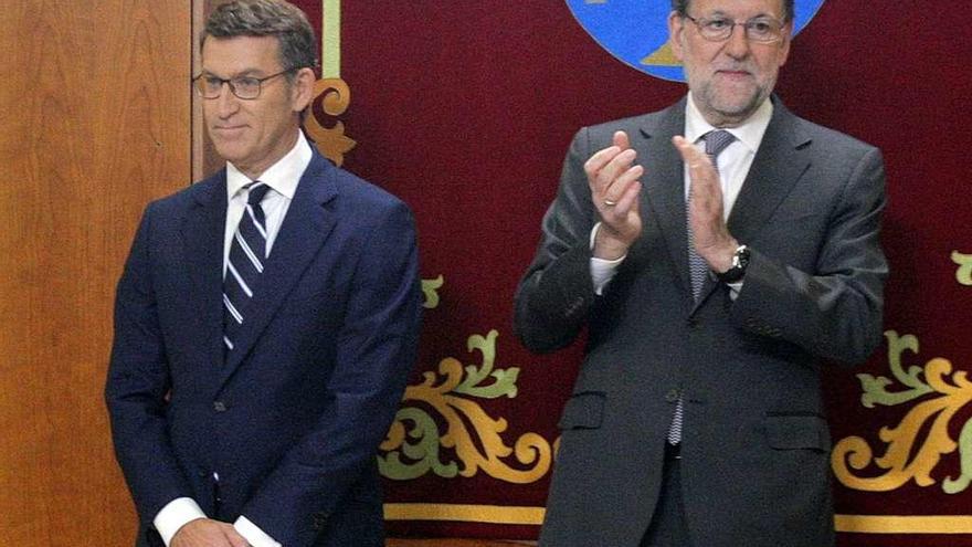 Rajoy aplaude a Feijóo tras tomar posesión de su cargo en el Parlamento de Galicia.