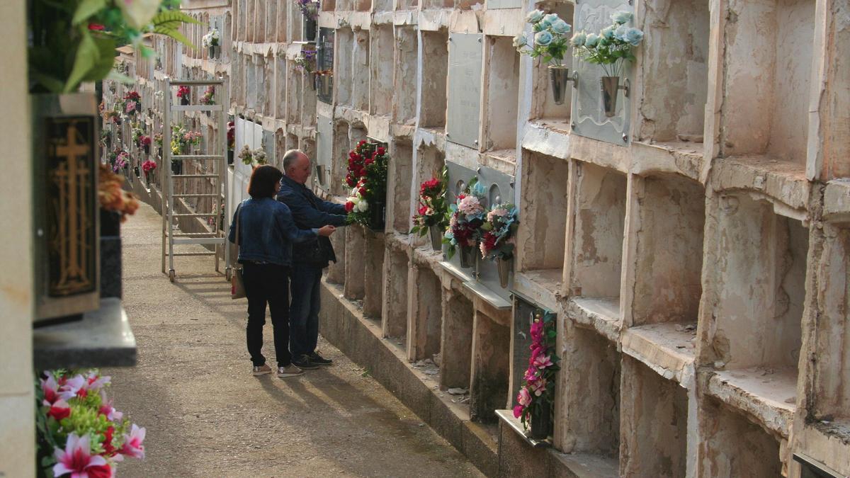 Dos personas colocan flores en un nicho de una de las calles más viejas del cementerio que están siendo vaciadas para derribarlos y construir nuevos pabellones.