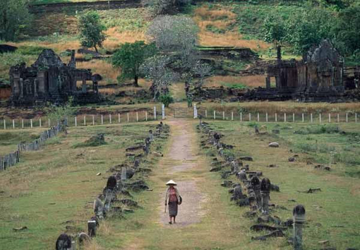 Una mujer camina a través de las ruinas de Wat Phu.