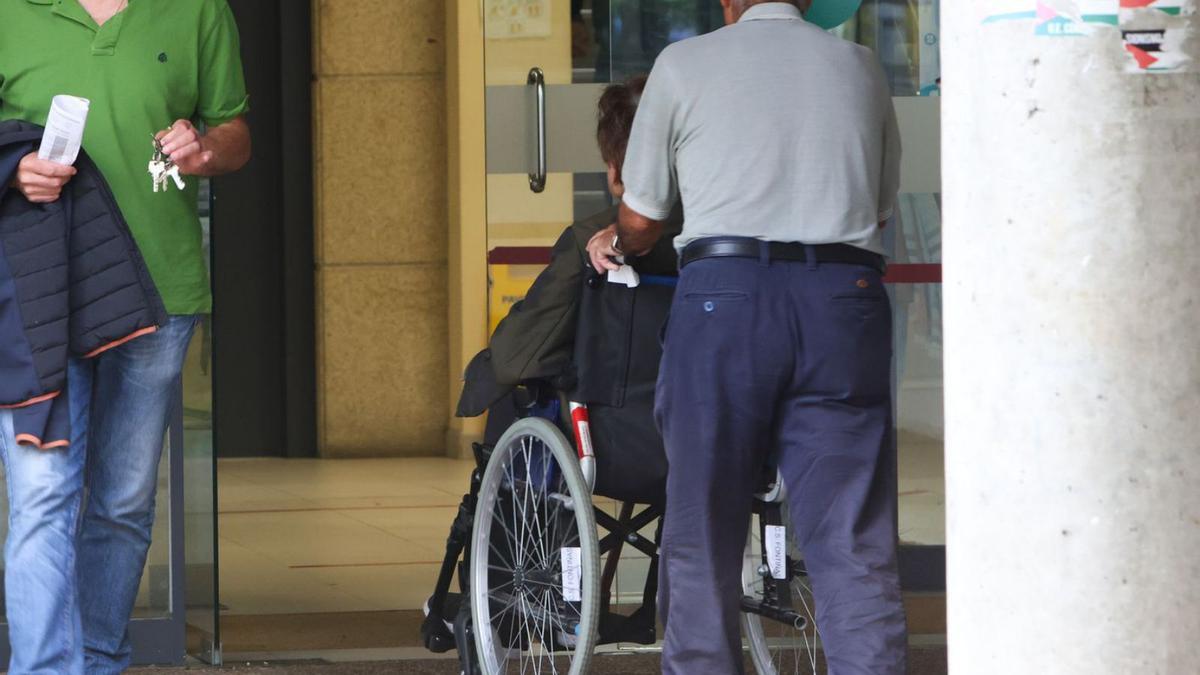 Un hombre empuja la silla de ruedas de una mujer a la entrada de un centro de salud.