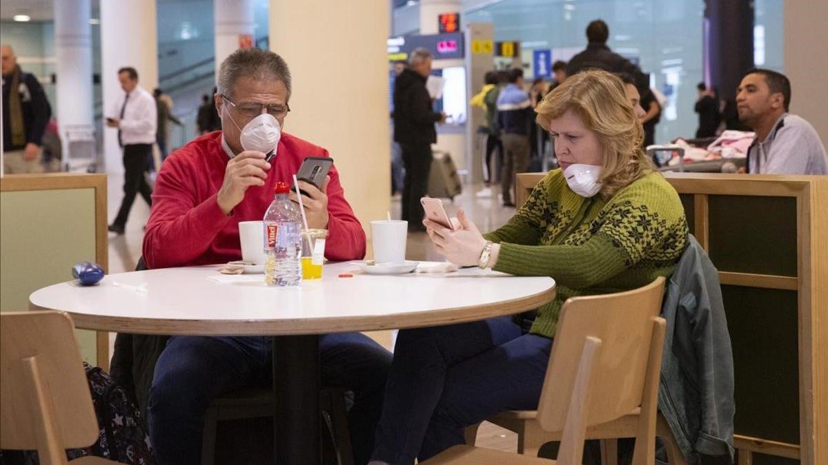 Dos personas con mascarilla protectora en el Aeropuerto de El Prat