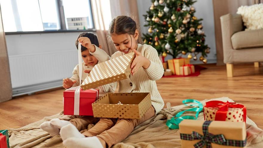 Dos niños abriendo regalos. | SHUTTERSTOCK
