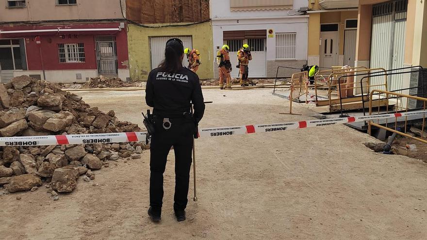 Una agente acordona la zona, mientras los bomberos al fondo contienen la fuga