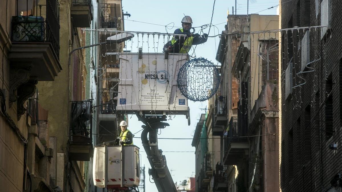 Un operario coloca unas luces de Navidad en una calle de Barcelona.