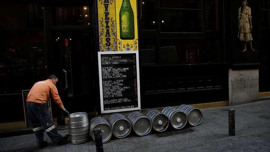 Un repartidor prepara el reparto de bidones de cerveza ante un restaurante.