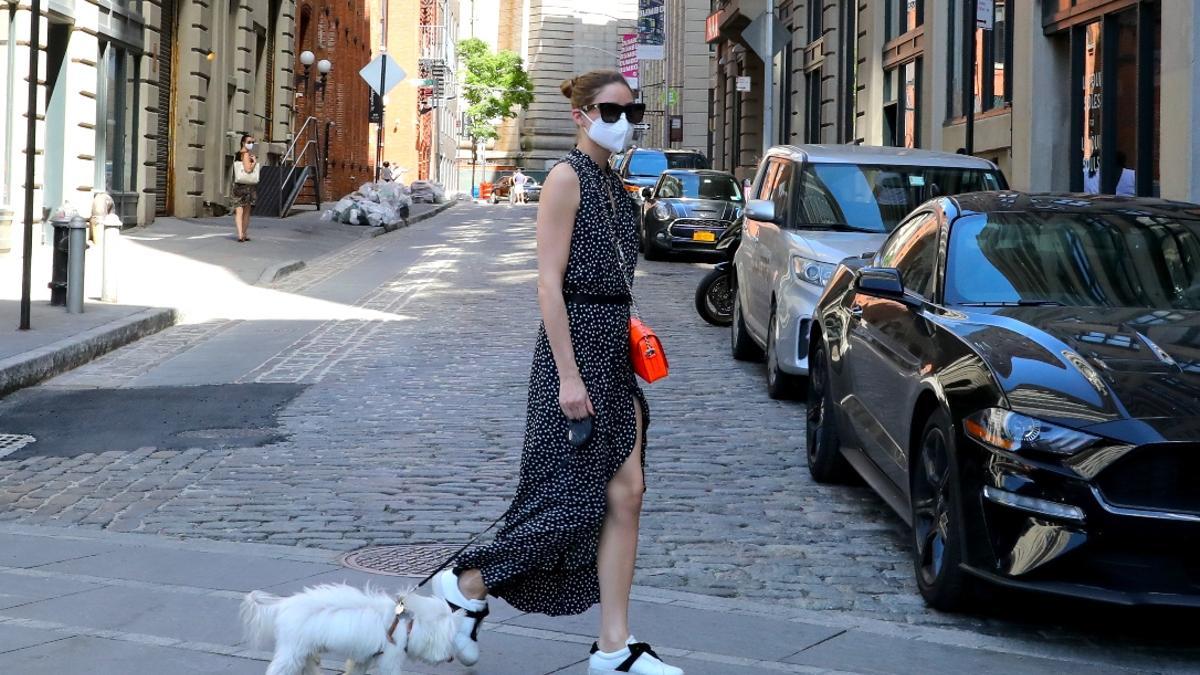 Olivia Palermo con vestido negro, zapatillas blancas y bolso naranja