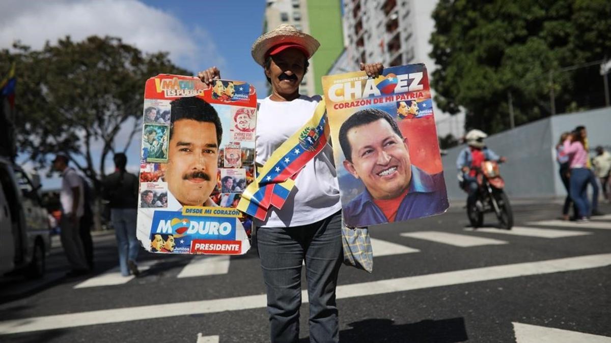 Una simpatizante de Maduro sostiene un cartel del mandatario y otro de Hugo Chávez  en una manifestación en Caracas.