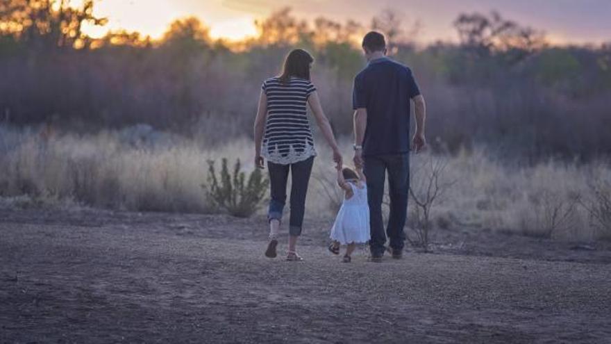 Unos padres pasean con su hija adoptiva.