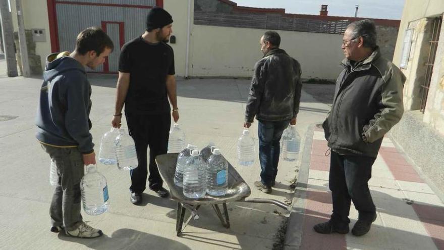 Un grupo de vecinos de Tardobispo recoge garrafas de agua para el consumo doméstico.