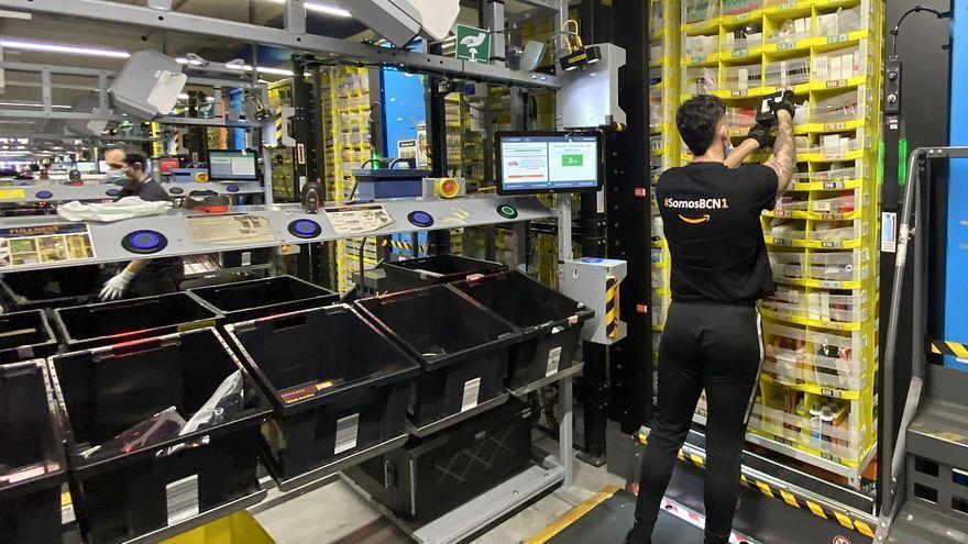 Un empleado de Amazon introduce productos en una estantería robotizada de la planta de El Prat.