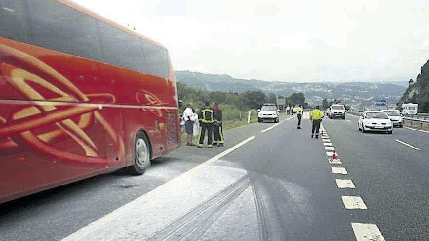 El autobús siniestrado y la Guardia Civil regulando el trafico ayer en la A-52. // FdV