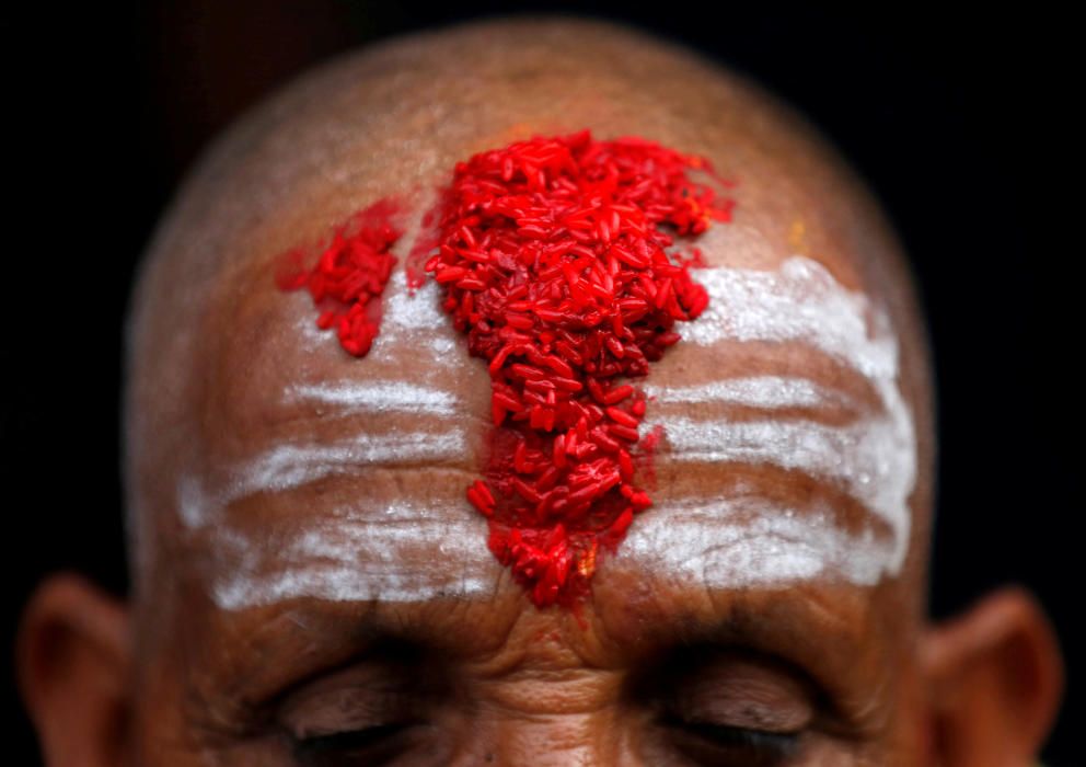 A Hindu priest's forehead is covered with ...