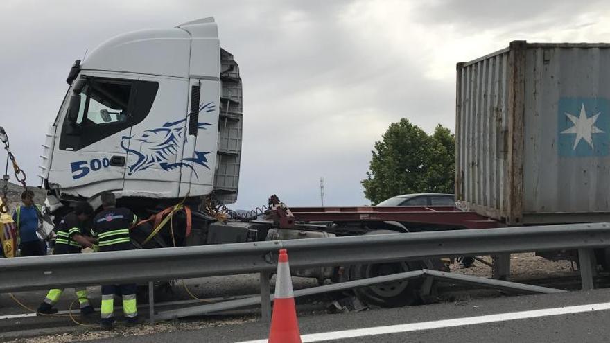 El personal de la grúa inmerso en las tareas para retirar el camión siniestrado en la autovía de Madrid