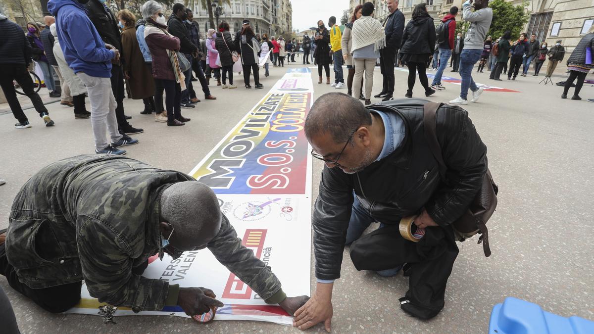 Varias personas colocan un cartel en la plaza del Ayuntamiento de València