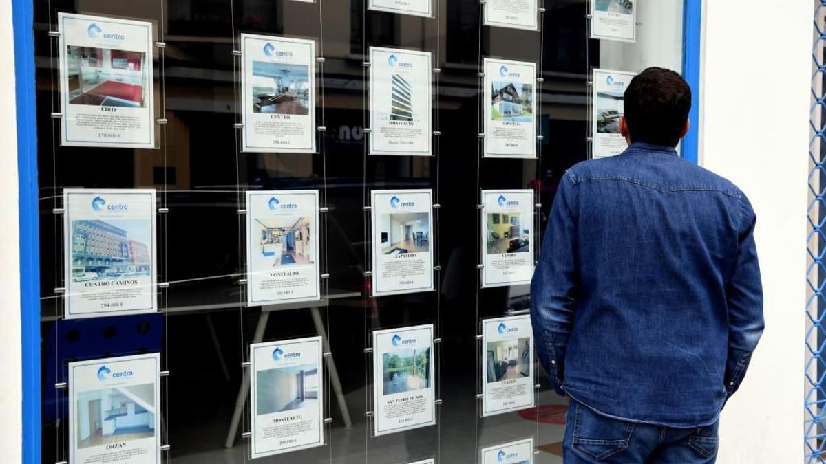 Un home mira els pisos en venda anunciats a l’aparador d’una immobiliària.