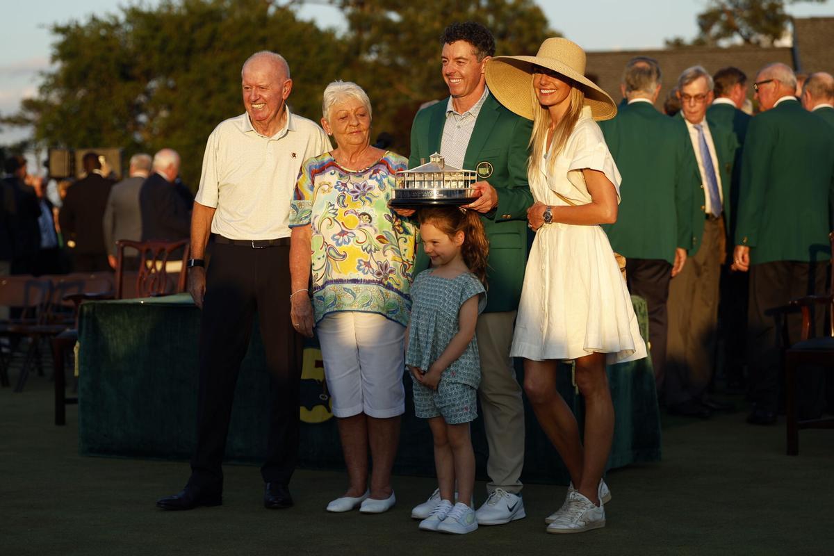 AUGUSTA (United States), 12/04/2026.- 2026 Masters tournament champion Rory McIlroy of Northern Ireland (C) poses with his parents, Gerry (L), mother, Rosie (2-L), wife Erica Stoll (R), and their daughter Popply while holding the trophy and wearing the Green Jacket after winning the final round of the 2026 Masters tournament in Augusta, Georgia, USA, 12 April 2026. (Irlanda) EFE/EPA/CHRIS TORRES