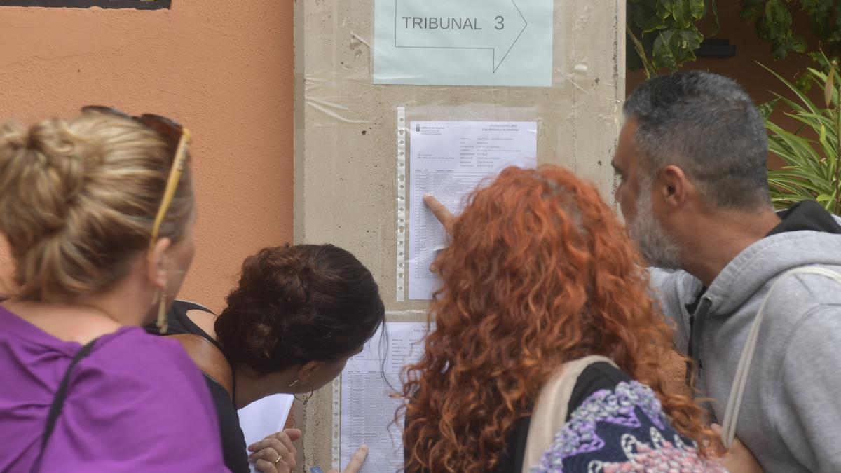 Opositores leyendo un documento en un tablón.