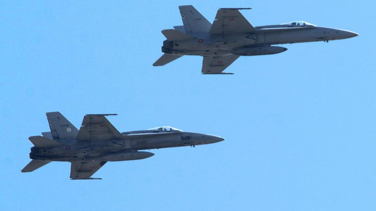 Dos aviones F-18 de las fuerzas aéreas españolas sobrevuelan la base de Morón de la Frontera, en Sevilla.