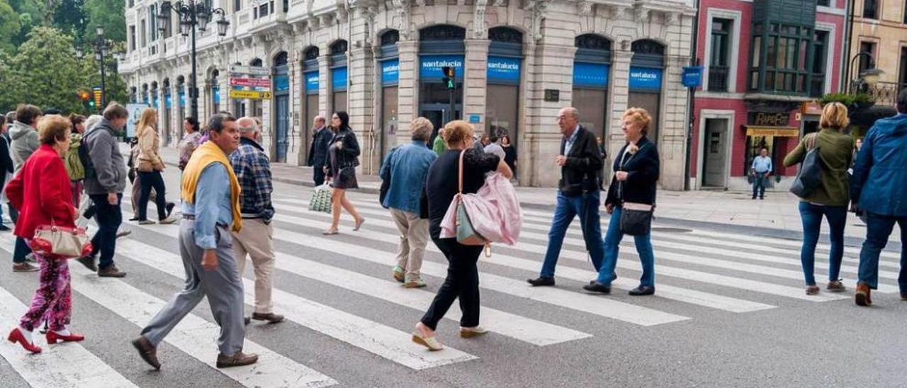 Peatones cruzando la calle de forma correcta por un paso de cebra, ayer, en Argüelles.