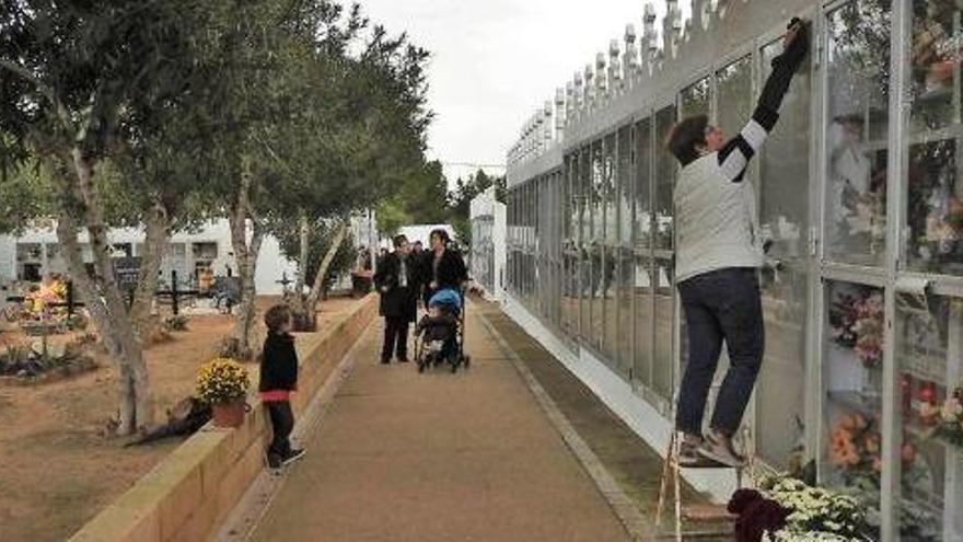 Una persona limpia en uno de los accesos principales del cementerio. Al fondo, varias familias.