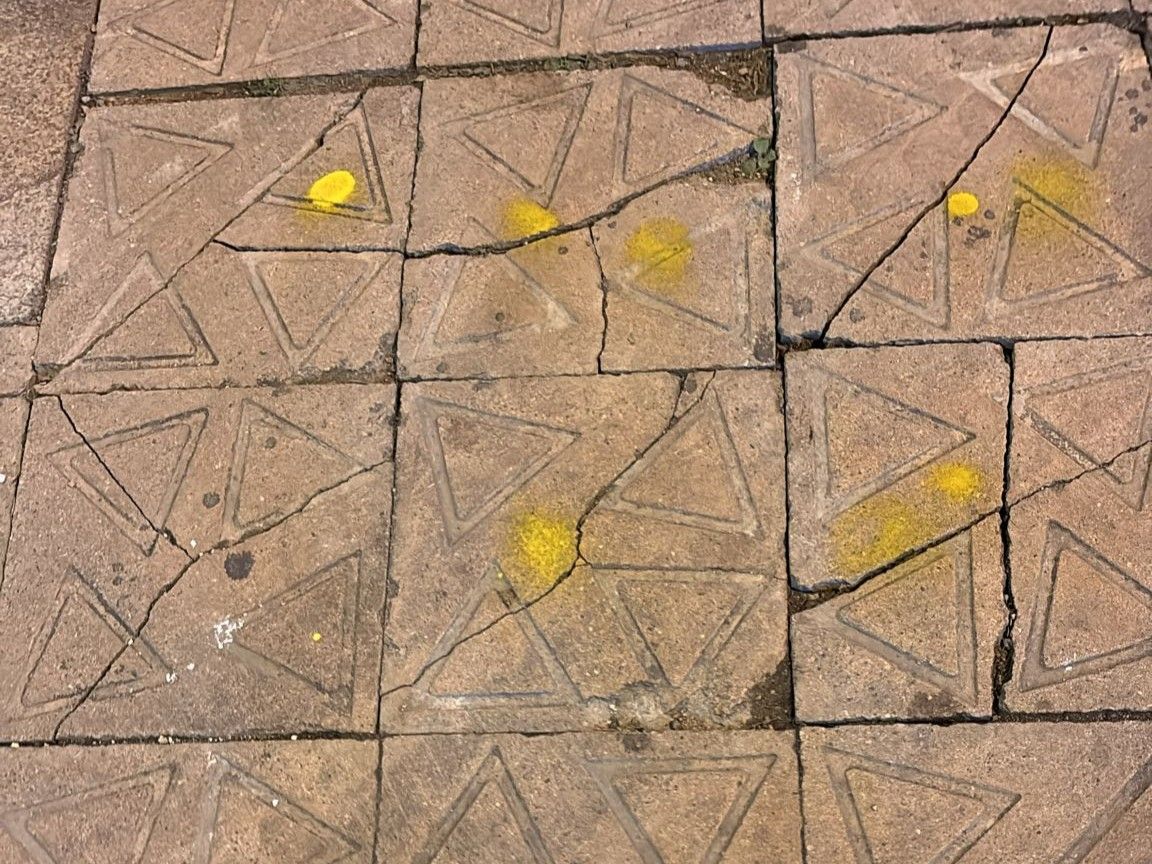 Baldosas fracturadas y marcadas con pintura amarilla en la Gran Via, en Barcelona.