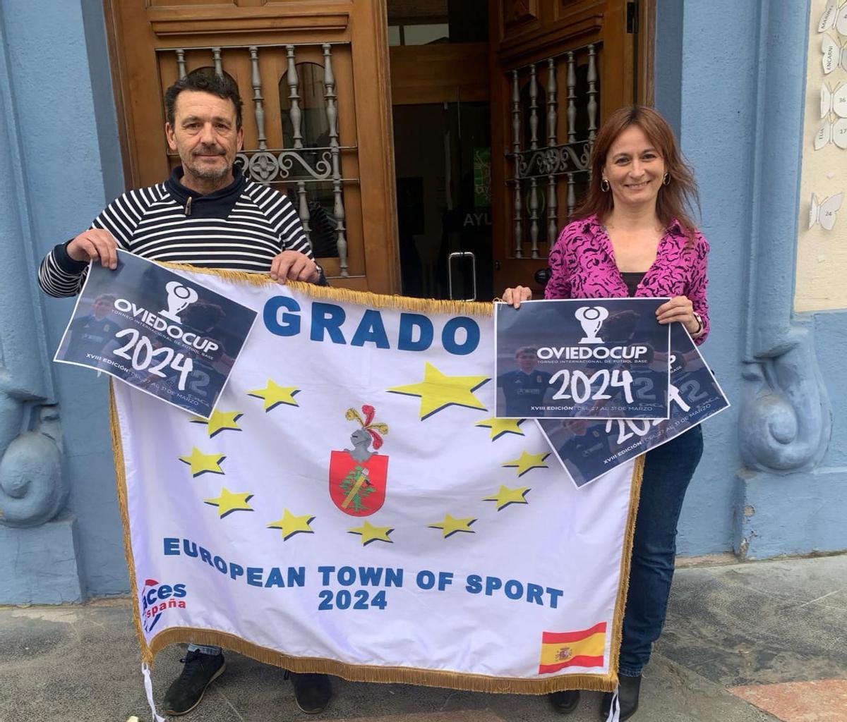 Chus Hevia y Lorena Álvarez Cabo, con la cartelería de la Oviedo Cup y la bandera de la Villa Europea del Deporte.