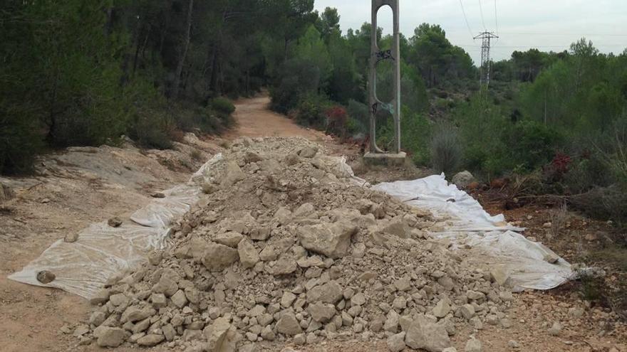 Una lona y piedras protegen huellas de carro de un antiguo camino.