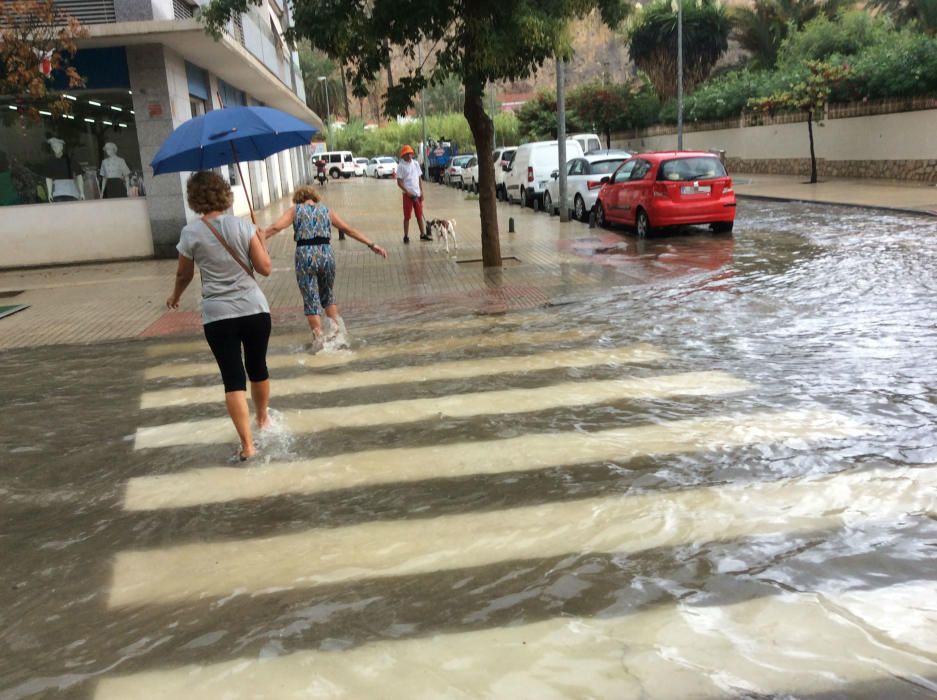 Los peatones tratan de cruzar por las calles anegadas de agua en Dénia.