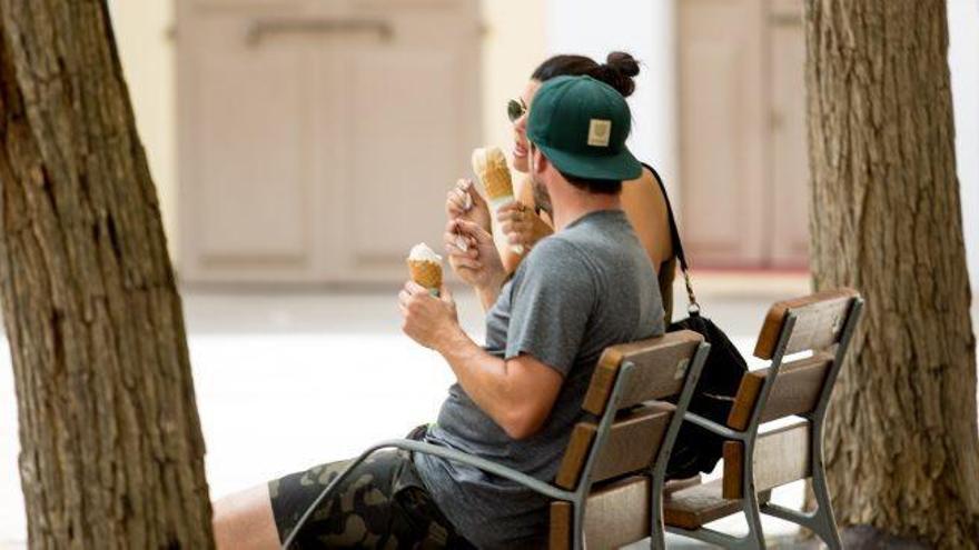 Una pareja de turistas saborea un helado en un banco.