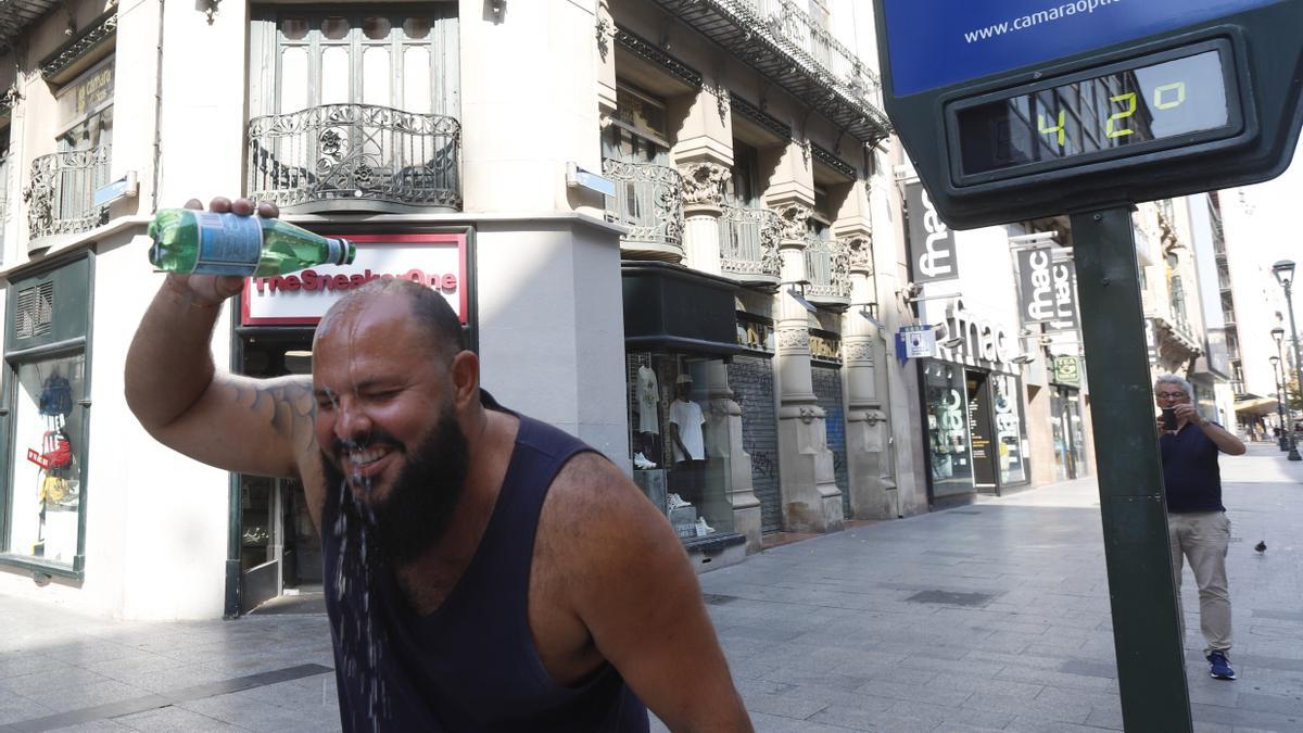 Un hombre se echa una botella de agua por la cabeza para refrescarse