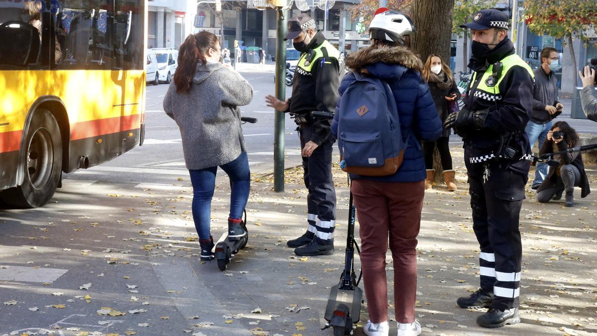 La Policia Municipal de Girona informant dues usuàries de patinets elèctrics a la plaça Marquès de Camps de Girona