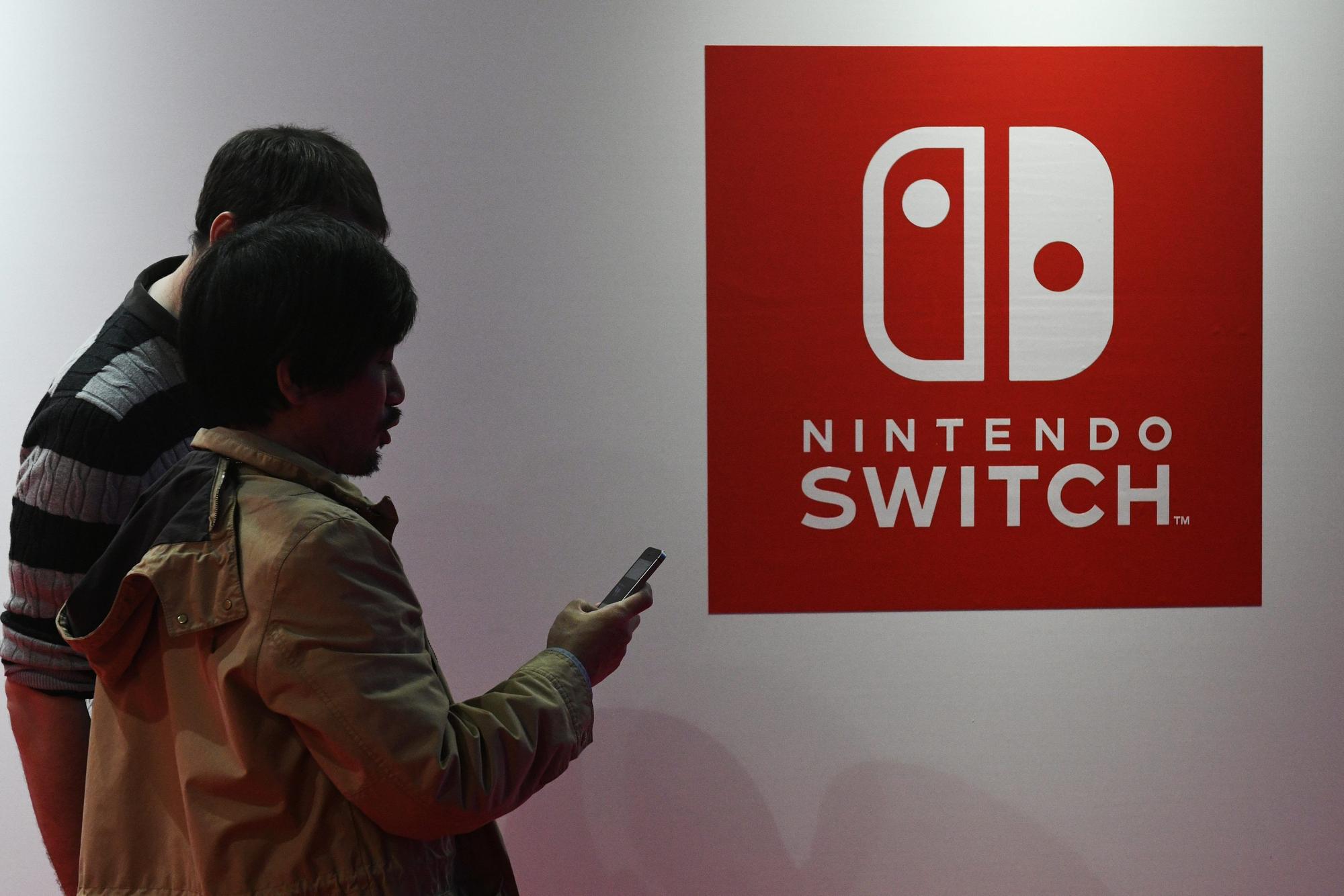 Dos hombres pasean ante un logo de Nintendo Switch
