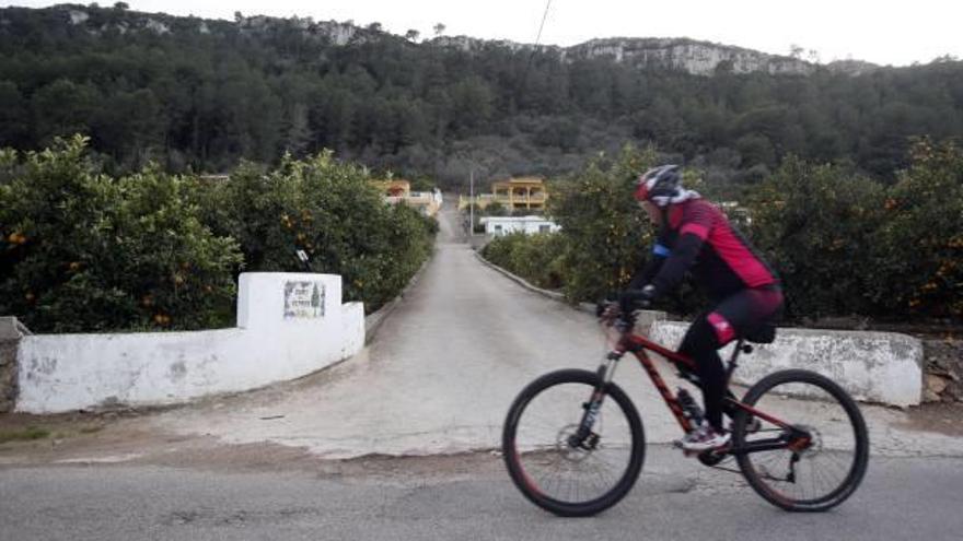 Un ciclista, ayer, pasa por la entrada del Camí del Xiprer, por el que subieron los bomberos.