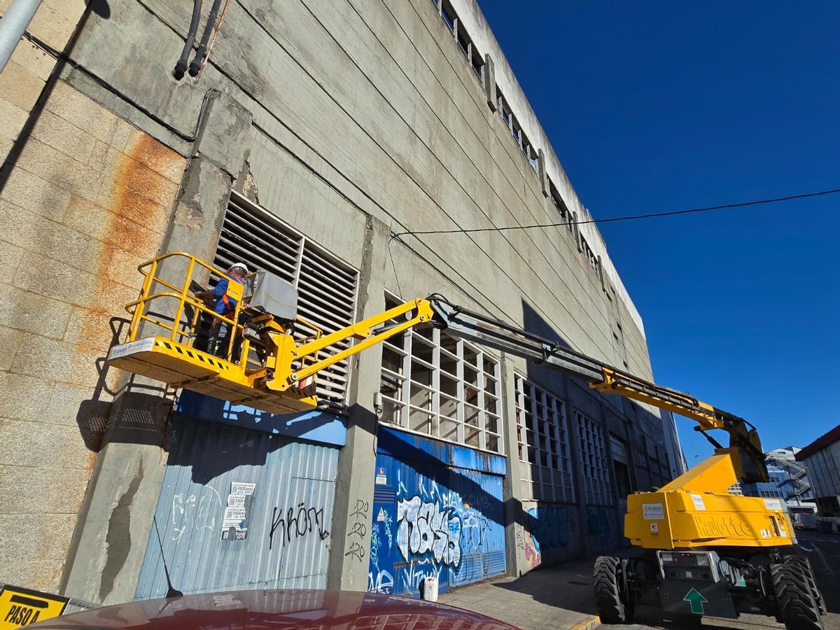 Uno de los obreros trabajando sobre la fachada trasera de la ruinosa nave.