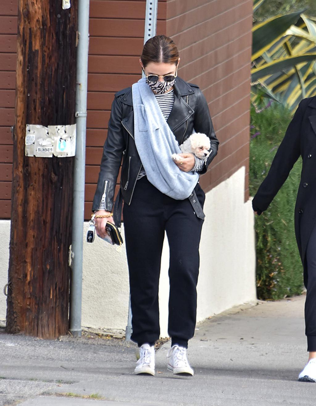 Lucy Hale, con pantalones jogger, biker y zapatillas Converse blancas. 